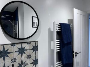 a bathroom with a mirror and a blue towel at Orchard Lodge -Coastal Retreat, new build, village views, private garden and terrace in Saint Brides Major