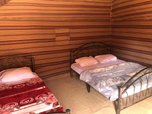 two beds in a room with wooden walls at Wadi Rum Bedouin Way Camp in Wadi Rum