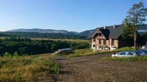 a house on a hill with cars parked next to it at WidziMiSie in Wetlina