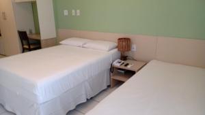 una camera con due letti e un tavolo con una lampada di Gran Lençóis Flat Residence a Barreirinhas