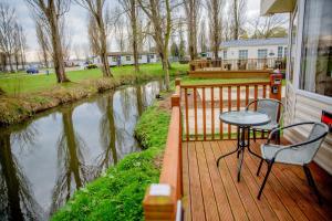 a wooden deck with a table and chair on a house at Billing Aquadrome Northampton lovely Waterside 2 Bedroom static holiday home Shemar in Northampton