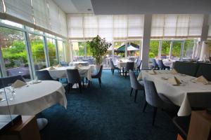 ein Restaurant mit weißen Tischen und Stühlen und Fenstern in der Unterkunft Strandhotel Fischland in Dierhagen