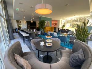 ein Restaurant mit Sofas, einem Tisch und Stühlen in der Unterkunft Strandhotel Fischland in Dierhagen