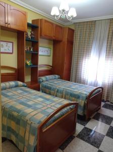 1 dormitorio con 2 camas y suelo a cuadros en Apartamento Turístico Antigua Universidad Almagro, en Almagro