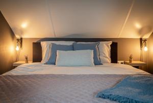 een slaapkamer met een groot bed met blauwe kussens bij 't Tuinhoes in Reuver