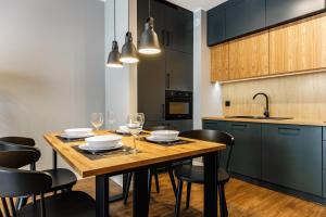 cocina con mesa de madera y sillas negras en Aparthotel Plac Litewski Premium en Lublin