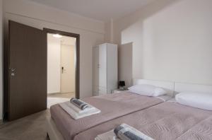 a white bedroom with two beds and a mirror at mansion luxury apartment in Psakoudia