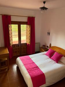 1 dormitorio con 1 cama grande y cortinas rojas en Hostal Ciudad Encantada, en Cuenca