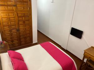 a bedroom with a bed with red and white sheets at Hostal Ciudad Encantada in Cuenca