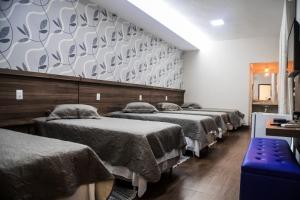 a row of beds in a room with a wall at A Fazenda eventos e lazer Lindomar Gonçalves in Piumhi