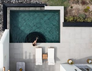 a swimming pool with a person in the water at Saint John Oia-Private Heated Pool Villas in Oia