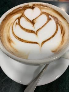 Una taza de capuchino con dos corazones pintados. en Hotel Candido, en Diano Marina