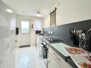 a kitchen with a sink and a stove top oven at Hazel House - Vibrant 2 bed house in Wishaw in Wishaw