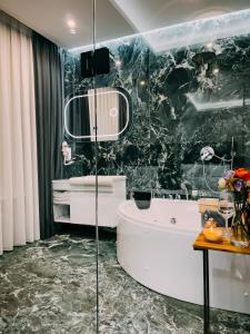 a bathroom with a white tub and a black marble wall at Imperator Hotel in Tirana