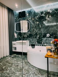 bagno con vasca bianca e parete in marmo nero di Imperator Hotel a Tirana