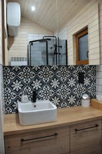 a bathroom with a sink and a black and white wallpaper at Domek Borsk nad samym jeziorem in Borsk