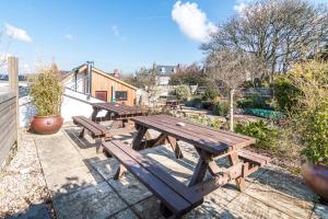 a group of wooden picnic tables in a garden at Manorbier Castle Inn Sunset Room in Tenby