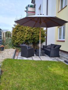a patio with an umbrella and two couches at Apartament Marco in Koszalin