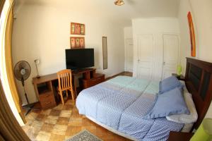Dormitorio con cama, escritorio y TV en Hostal del Cerro, en Santiago