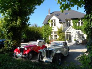 two old cars parked in front of a house at Hotel Martinique in Nieuwpoort
