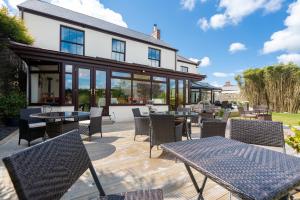 eine Terrasse mit Tischen und Stühlen vor einem Gebäude in der Unterkunft The Cedars in Redruth