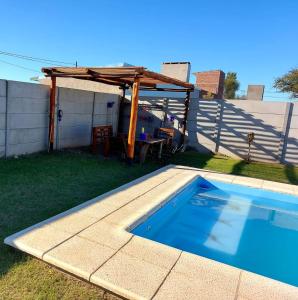 a backyard with a swimming pool and a wooden pergola at Cabaña Curacó in Santa Rosa