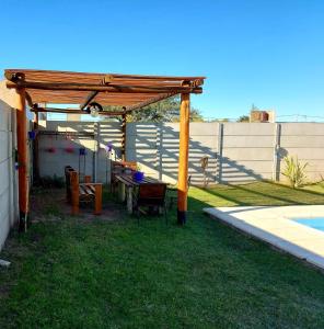 a wooden pergola with a table and chairs in a yard at Cabaña Curacó in Santa Rosa