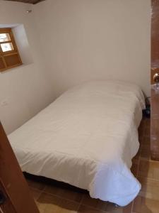 a white bed in a room with a window at Cabaña Eliseo Guachato Villa Rosita in Tota