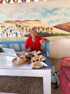 
a woman sitting at a table with a plate of food at The Mango Guest House in Aswan

