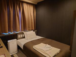 una piccola camera da letto con un letto e asciugamani di Hotel Relief SAPPORO SUSUKINO - Vacation STAY 22951v a Sapporo