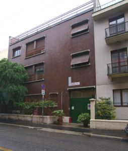 un bâtiment en briques avec une porte verte dans une rue dans l'établissement Hostel Colours, à Milan