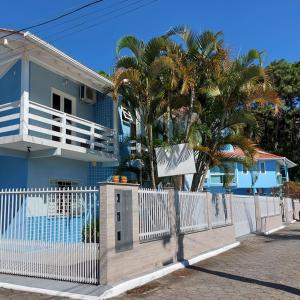 una casa azul con una valla blanca y palmeras en Pousada Estrela Guia, en Florianópolis