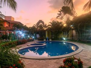 una piscina en un patio por la noche con luces en La Dolce Vita Flat & Pousada en Praia do Frances