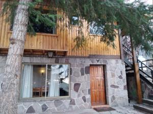 a cabin with a wooden door next to a tree at Hostal Boutique CUMBRES in Farellones
