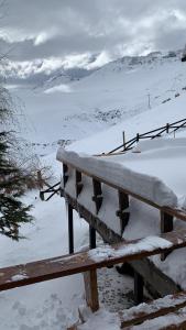 uma mesa de piquenique de madeira coberta de neve num campo em Hostal Boutique CUMBRES em Farellones