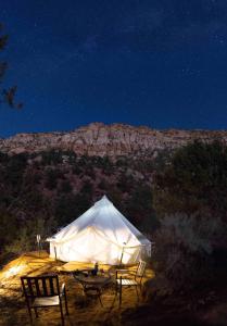 Zion View Camping في Hildale: خيمة بيضاء مع كراسي امام جبل