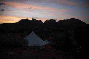 Zion View Camping في Hildale: خيمة بيضاء عند غروب الشمس مع جبال في الخلفية