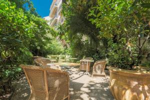 a patio with a table and chairs and trees at Le Windsor, Jungle Art Hotel in Nice