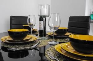 a dining room table with yellow plates and wine glasses at Hermoso Apartamento Central in Pereira