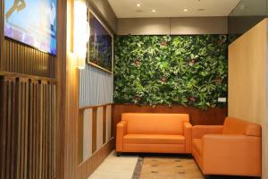 uma sala de espera com cadeiras laranja e uma parede verde em Orkid Hills Hotel em Kuala Lumpur