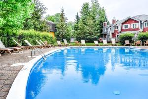 a large swimming pool with chairs and a house at Townhouse With Free Shuttle To Tremblant Resort in Mont-Tremblant