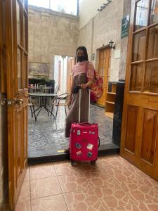 a woman is pulling a suitcase in a hallway at Hostal La Posada Del Sol in Arequipa +15 photos