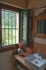 baño con lavabo, espejo y ventana en Casa Rural El Vihuelo, en El Bosque