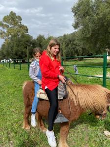 zwei junge Mädchen, die mit einem Kind auf einem Pony reiten in der Unterkunft Casa Rural El Vihuelo in El Bosque