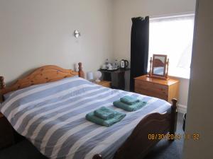 a bedroom with a bed with two green towels on it at Queen Mary Inn in Poole