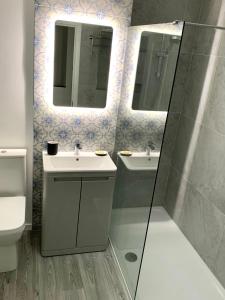 La salle de bains est pourvue d'un lavabo, de 2 miroirs et de toilettes. dans l'établissement La Brisa-fully refurbished, perfect local, à Portrush