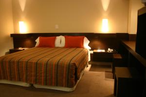 Habitación de hotel con cama con almohadas de color naranja en Hotel Cordon Del Plata en Mendoza