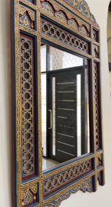 a mirror with a wooden frame on a wall at Al Ghadeer Maison Masfout in Sharīyah