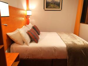 a bed in a hotel room with a white comforter at Amakonkay Machupicchu in Machu Picchu