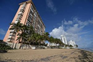budynek przy plaży z palmami i oceanem w obiekcie KASA Las Palmas studio apt for 2 OCEAN VIEW BEACHFRONT CONDO POOL w mieście San Juan